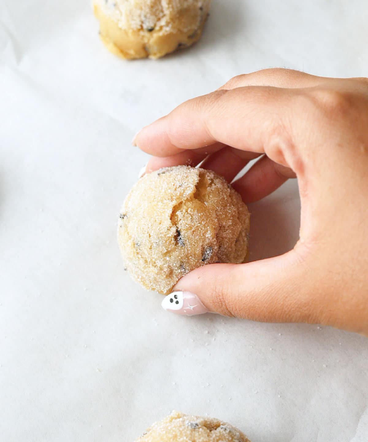 Placing an earl grey cookie dough ball on a lined baking sheet.