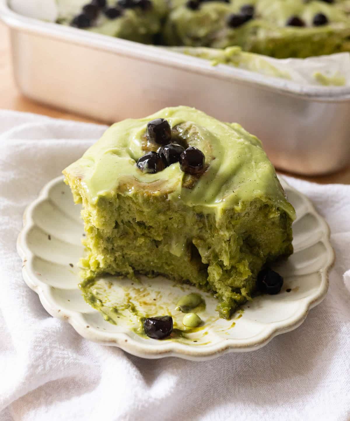 Brown sugar matcha roll with bite taken out on top of a white fluted plate.