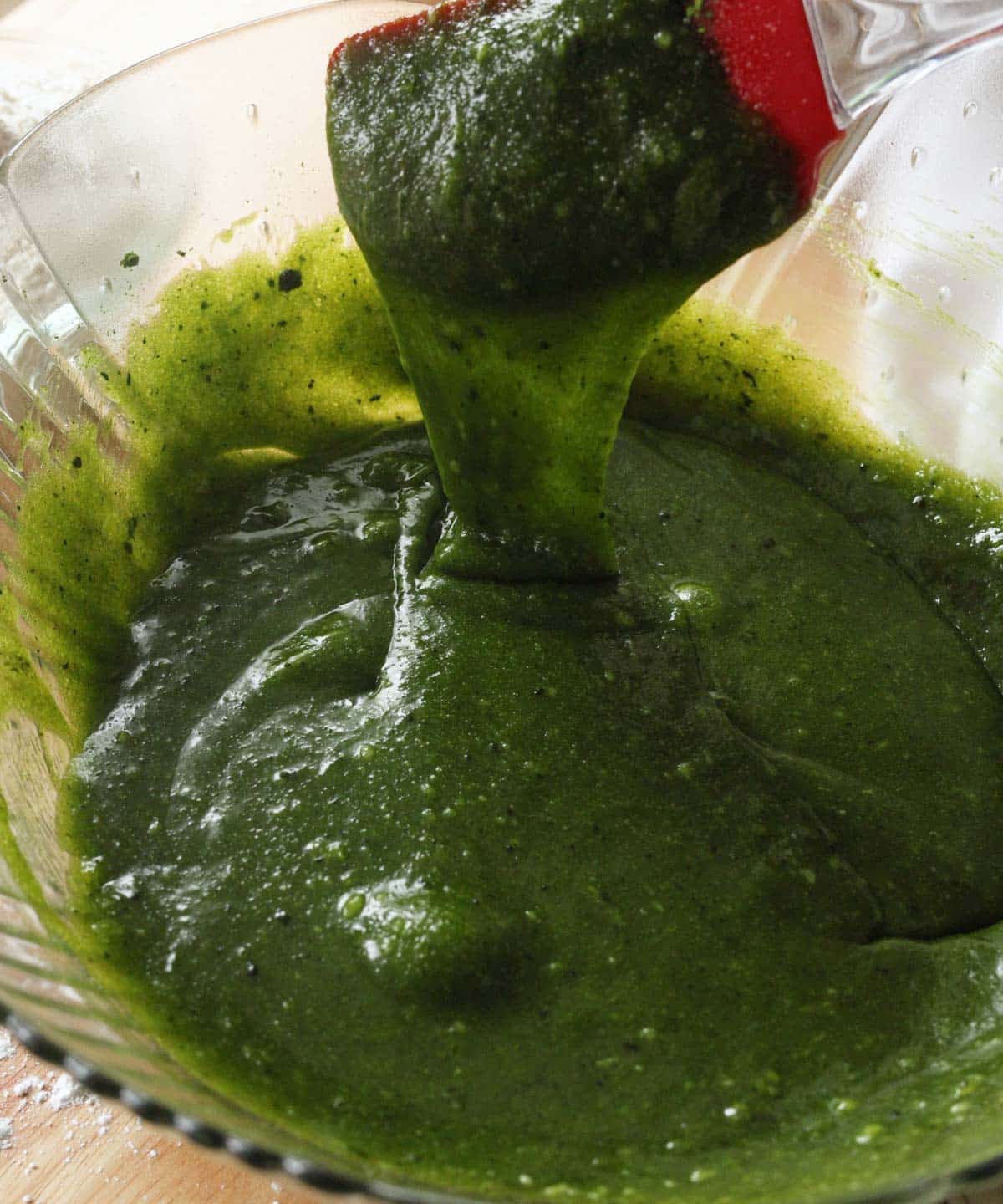 Wet ingredients mixed in a glass mixing bowl, ribboning off spatula.