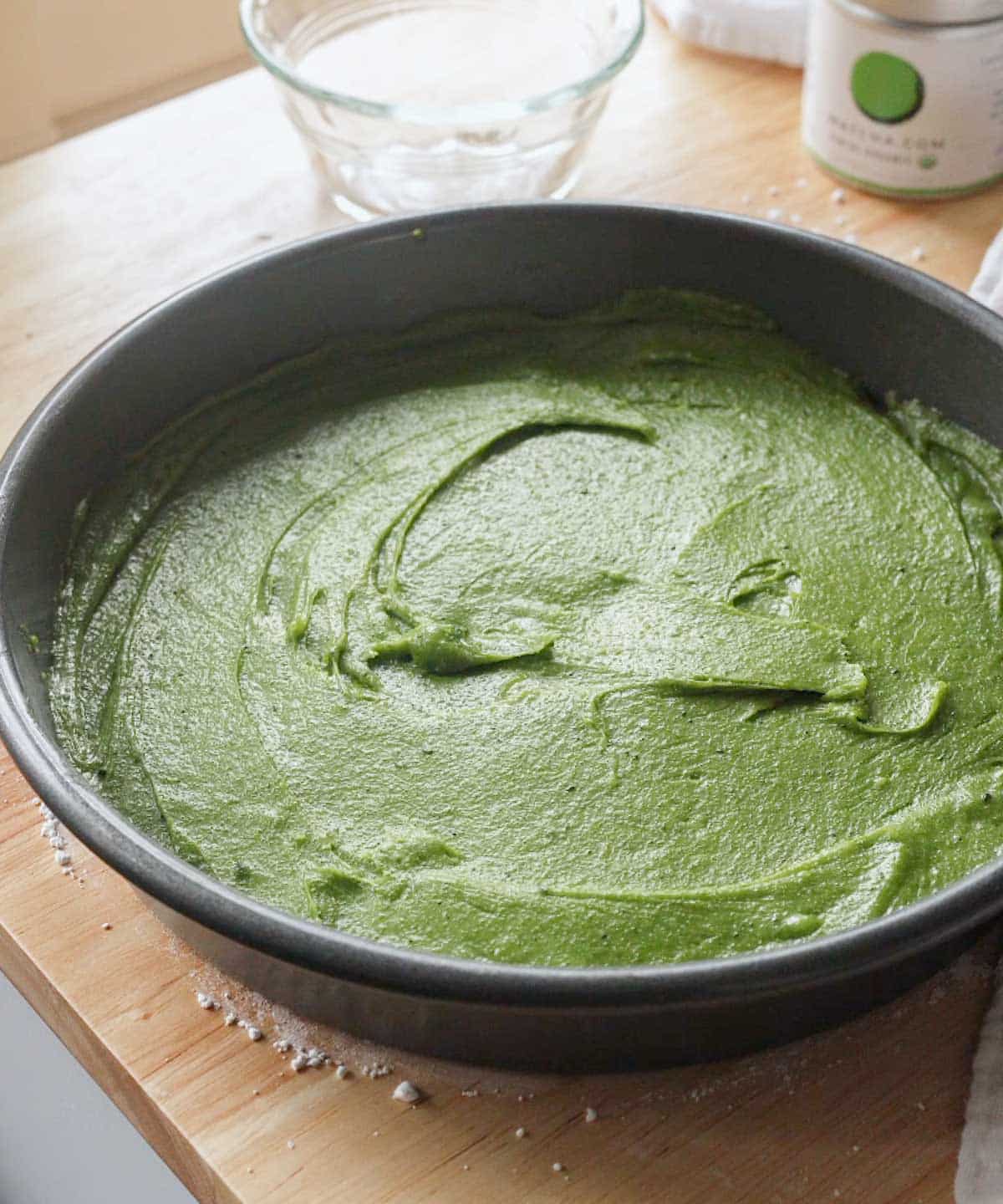 Matcha brownie batter in circle cake pan ready to be baked.