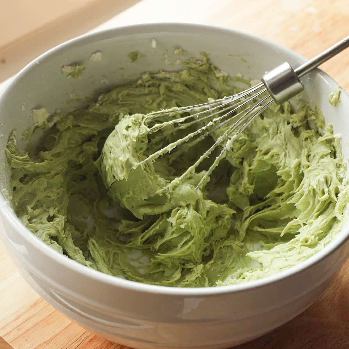 Fluffy matcha cream cheese frosting in a white mixing bowl.