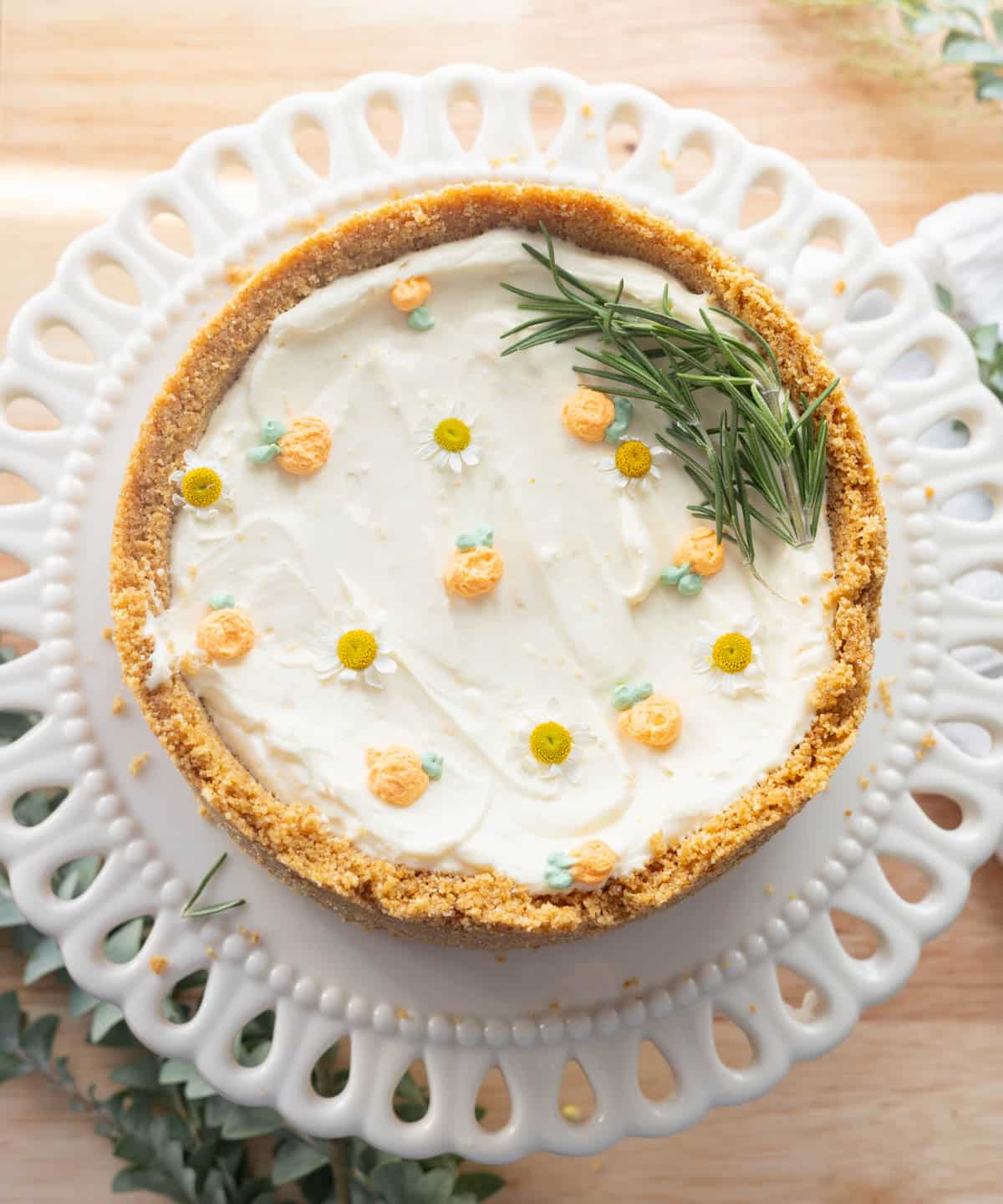 No-bake orange cheesecake decorated with whipped cream, edible flowers, and rosemary.