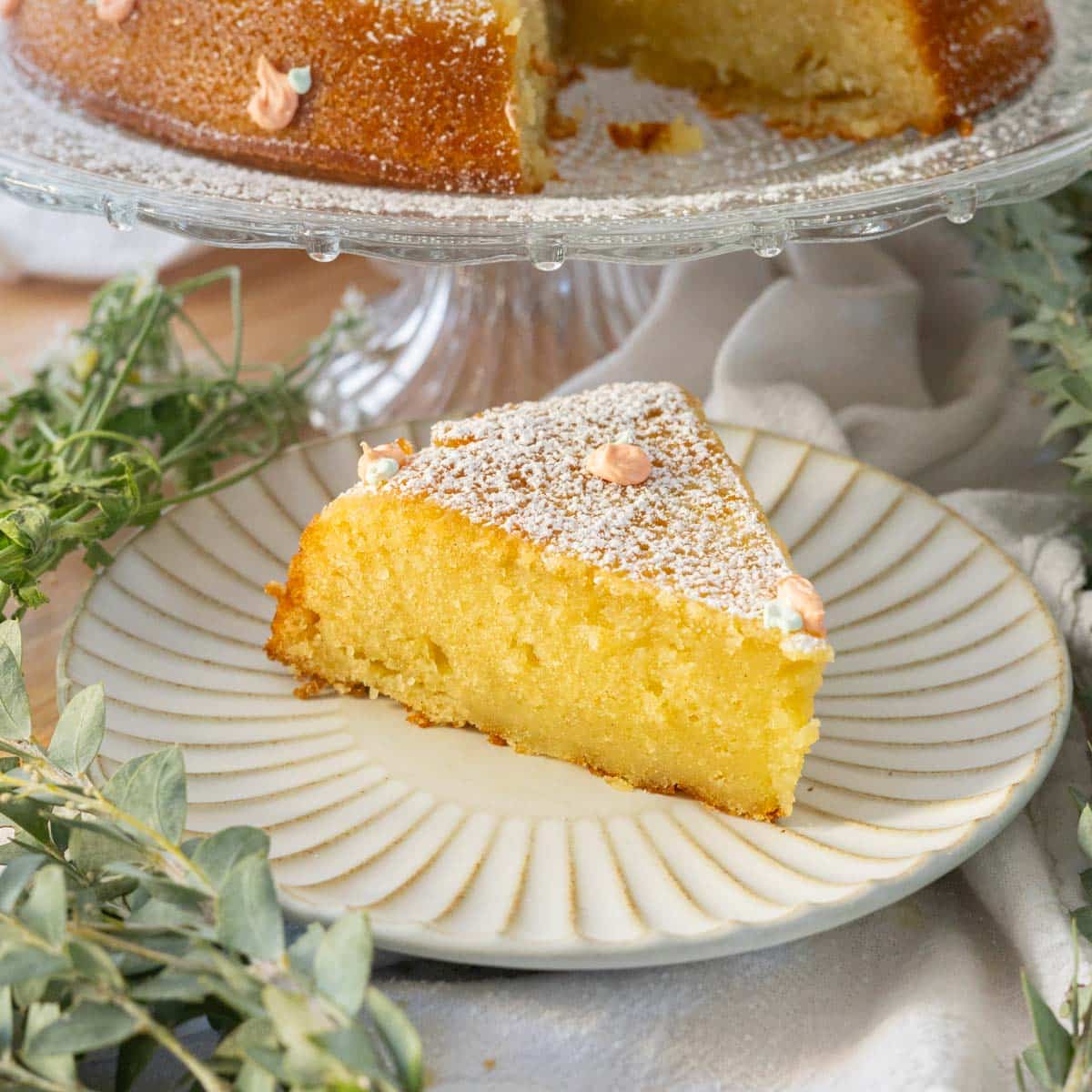 Slice of orange olive oil cake on a fluted plate.