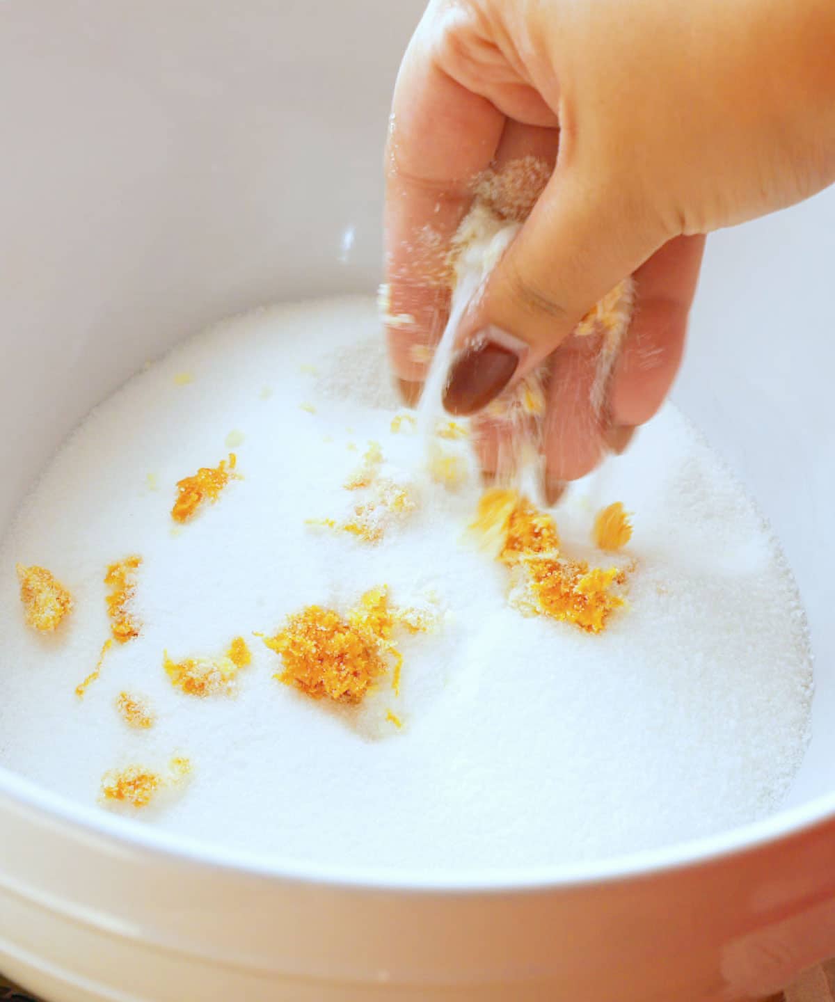 Massaging orange zest into sugar until fragrant.