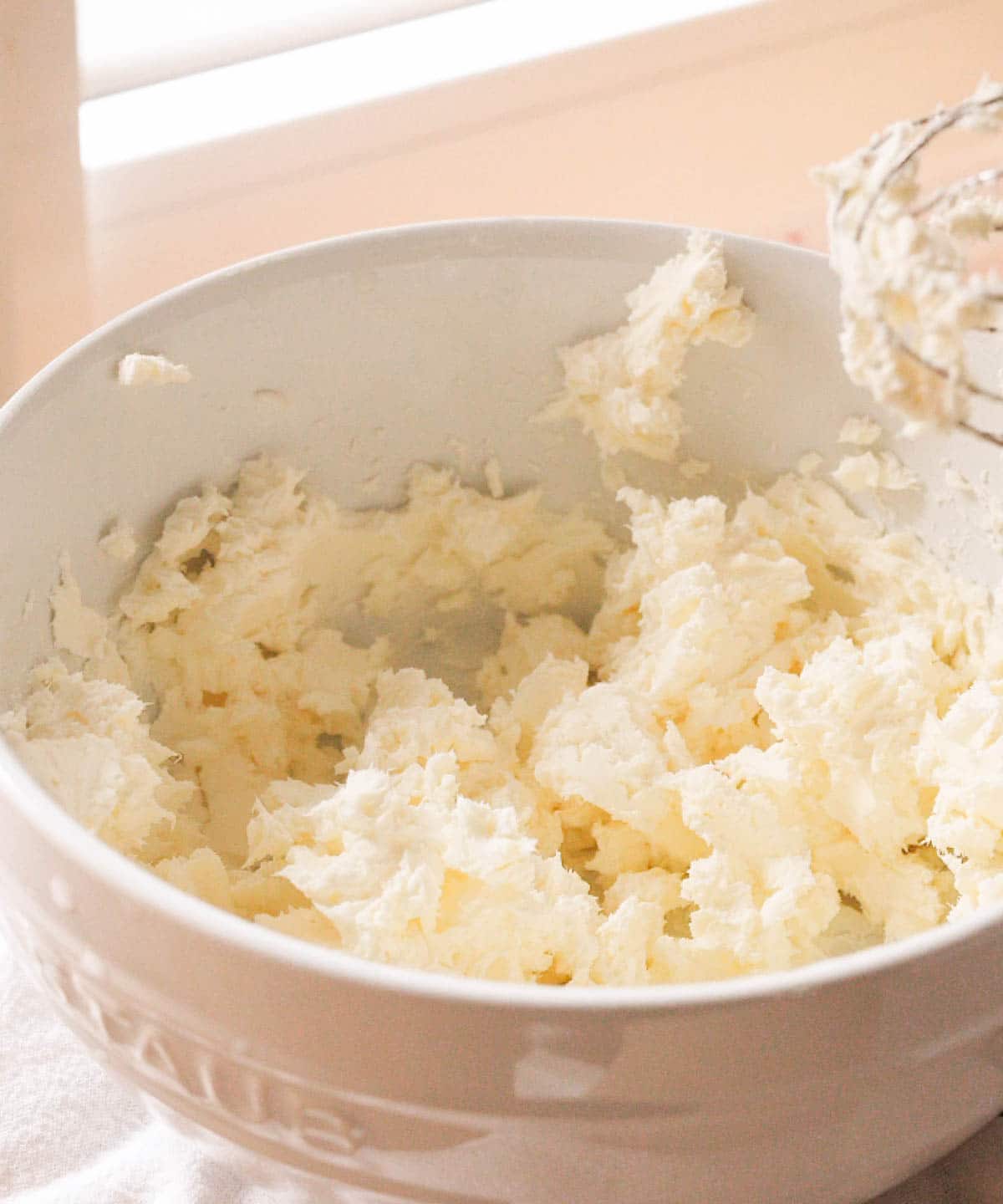 Whipped cream cheese in white mixing bowl.