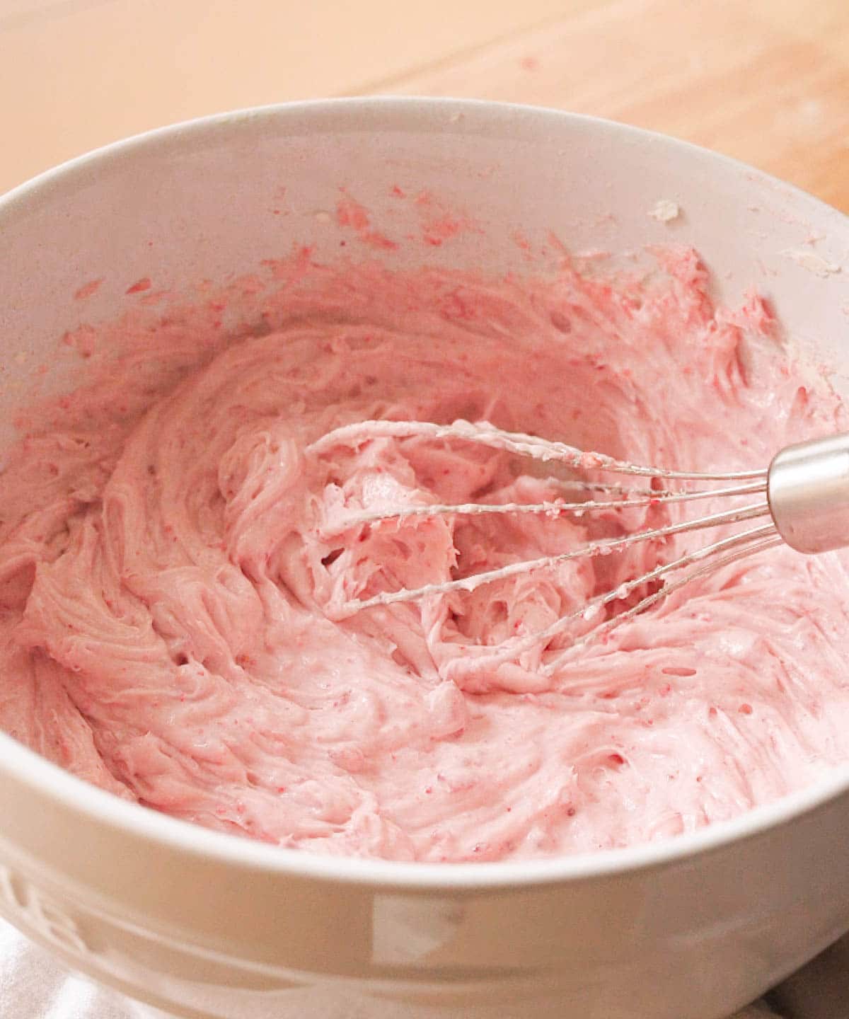 Finished strawberry frosting in white mixing bowl.