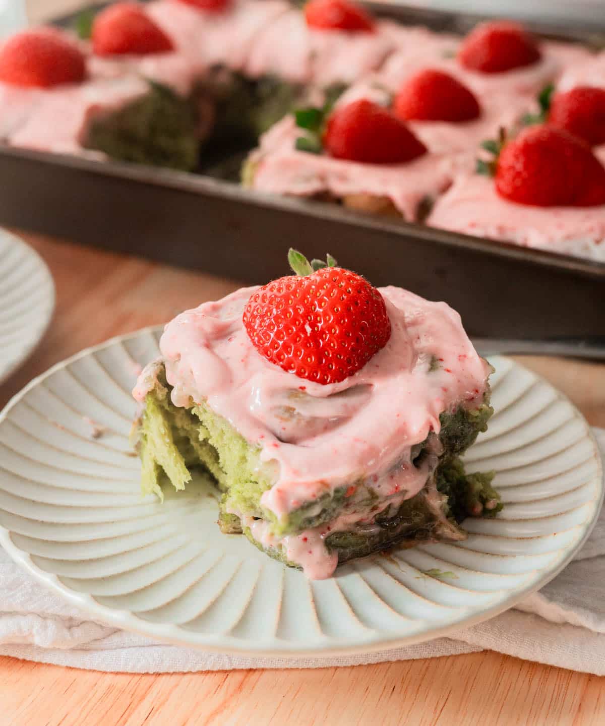 Strawberry matcha roll on a white fluted plate.