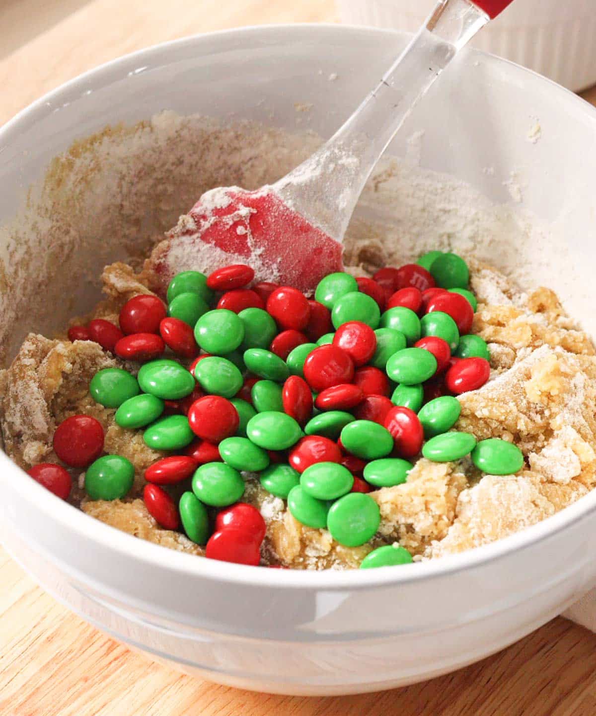 Red and green M&Ms poured on top of cookie dough batter.