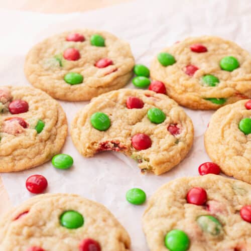 Red and green M&M cookies on parchment paper.