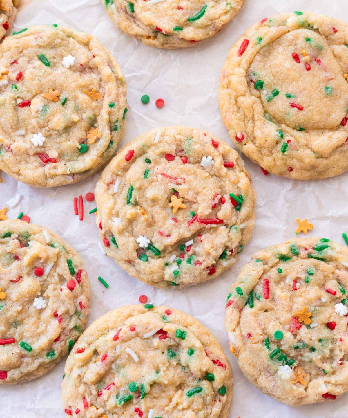 Cute red and green Christmas sprinkle cookies on parchment paper.