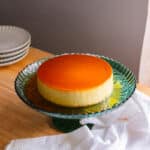 Coconut leche flan on a rimmed green cake stand.