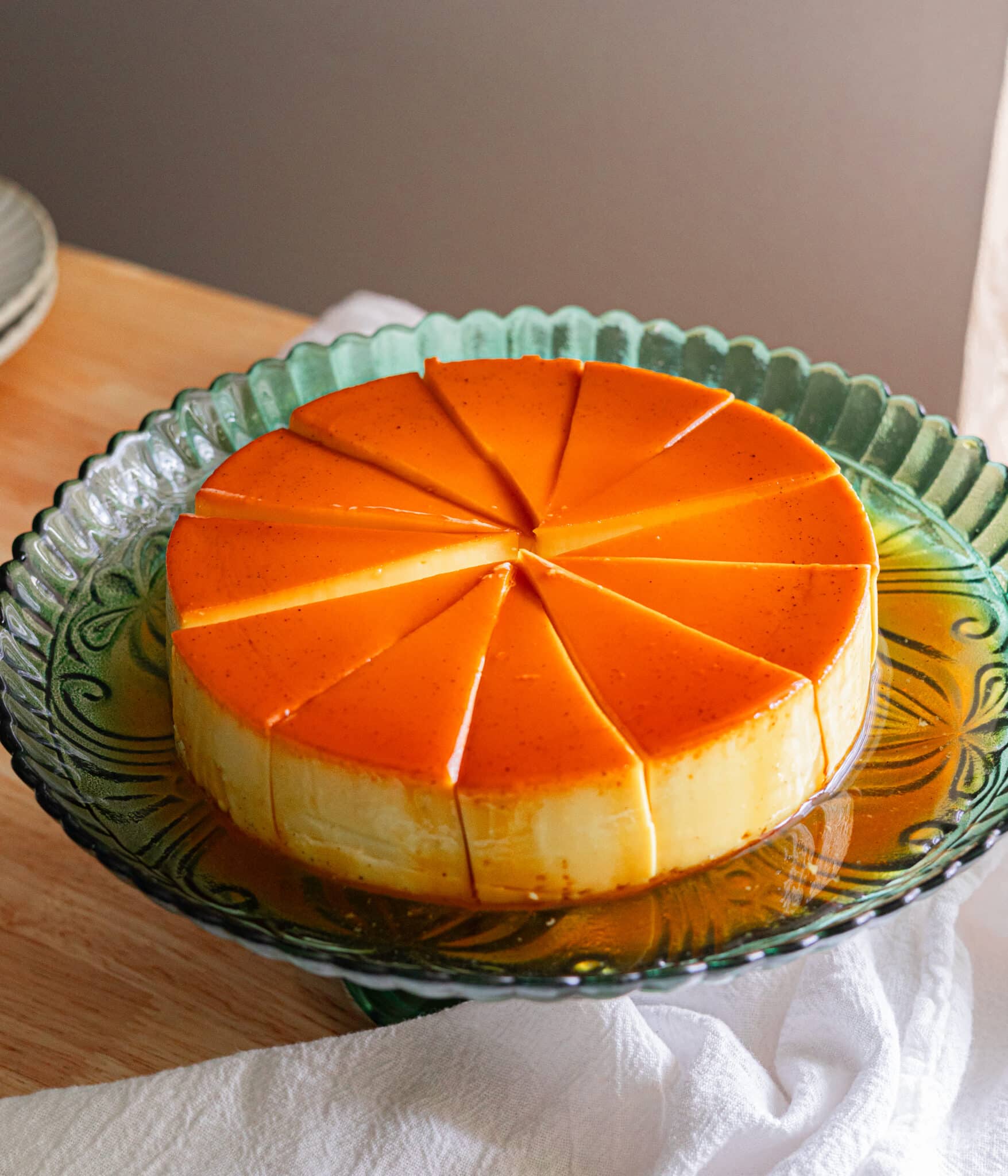 Sliced coconut flan on a green cake stand.
