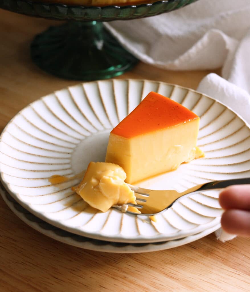 Slice of coconut leche flan on fluted plate.