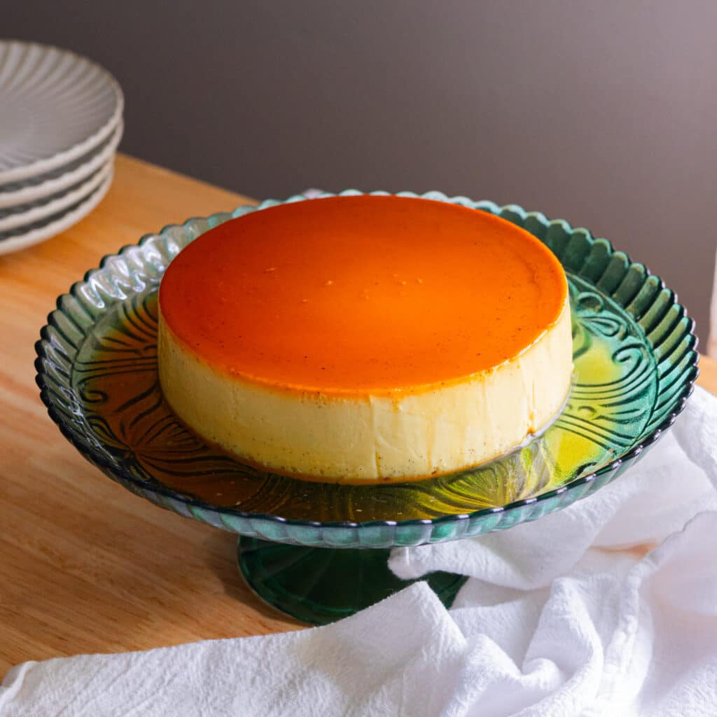 Coconut leche flan on a rimmed green cake stand.