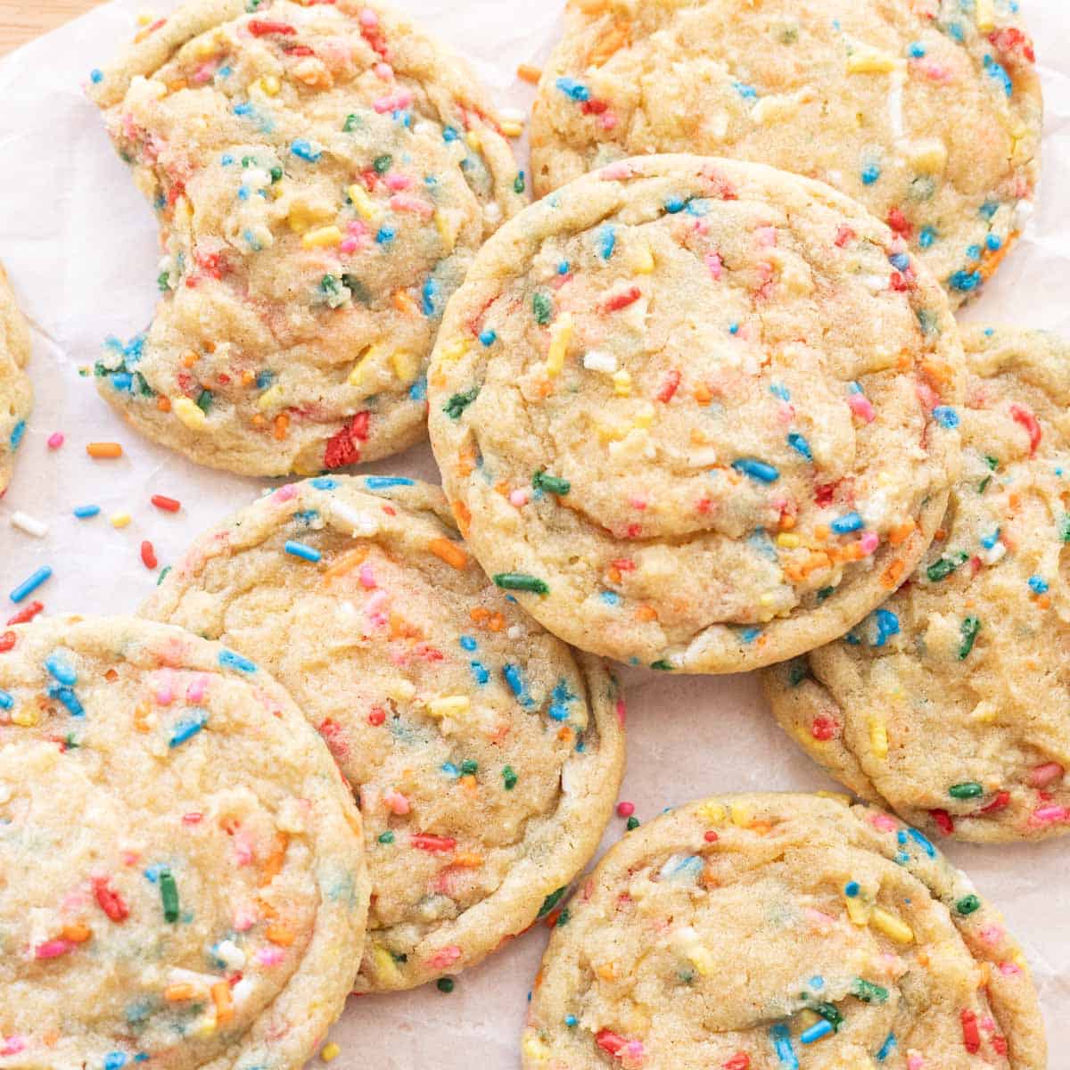 Rainbow funfetti cookies on white parchment paper.