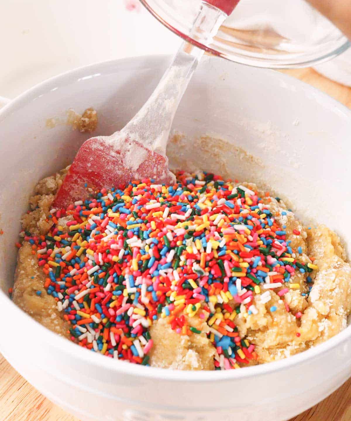 Rainbow sprinkles poured on top of cookie dough batter.