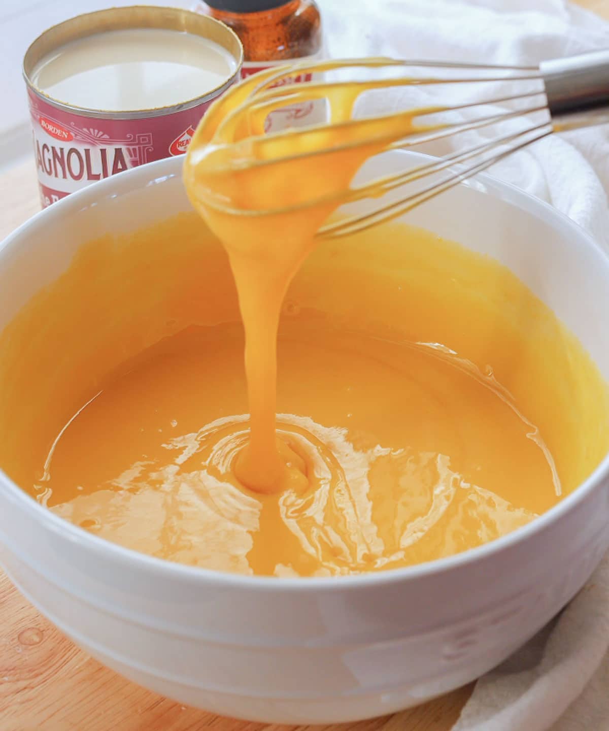 Egg yolks and condensed milk mixed together in a white bowl.