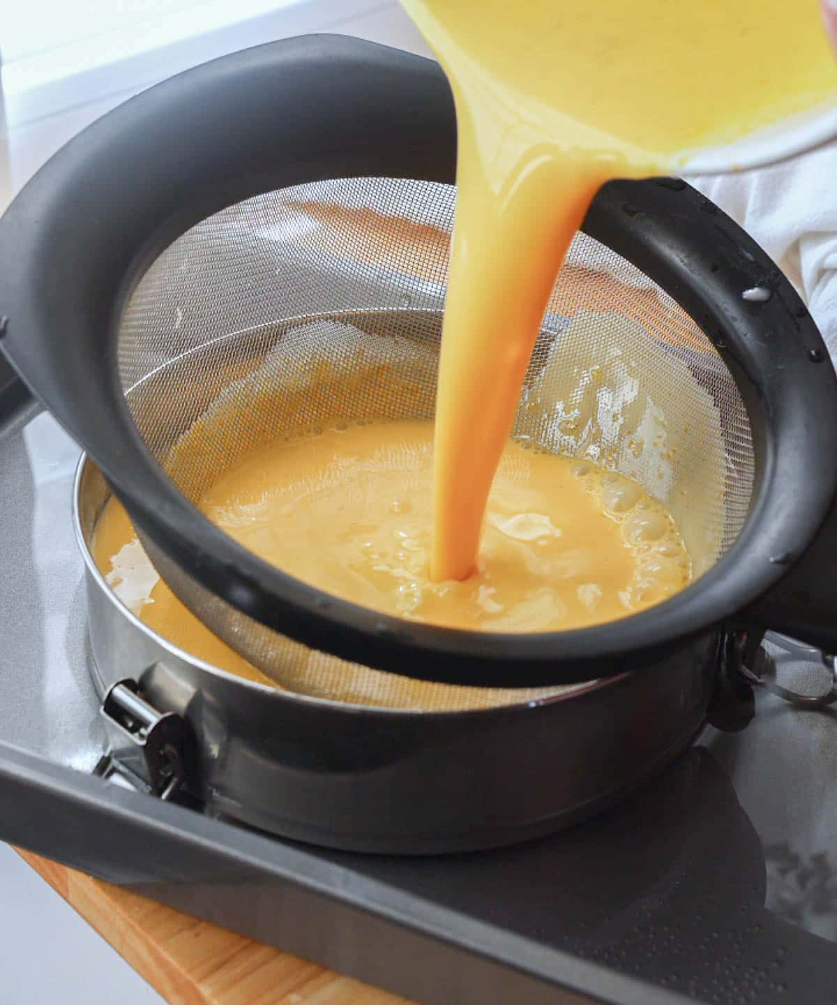 Pouring leche flan batter through sieve into llanera.