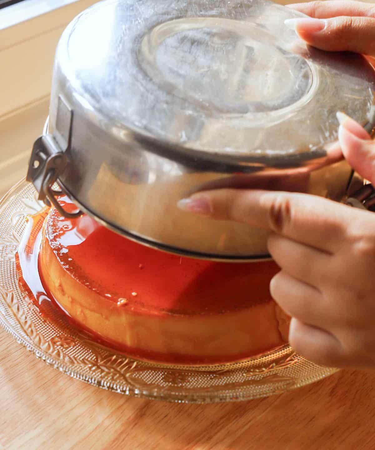 Turning out leche flan onto a glass serving plate.