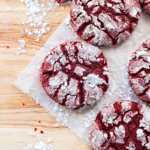 Red velvet crinkle cookies on a wooden table.