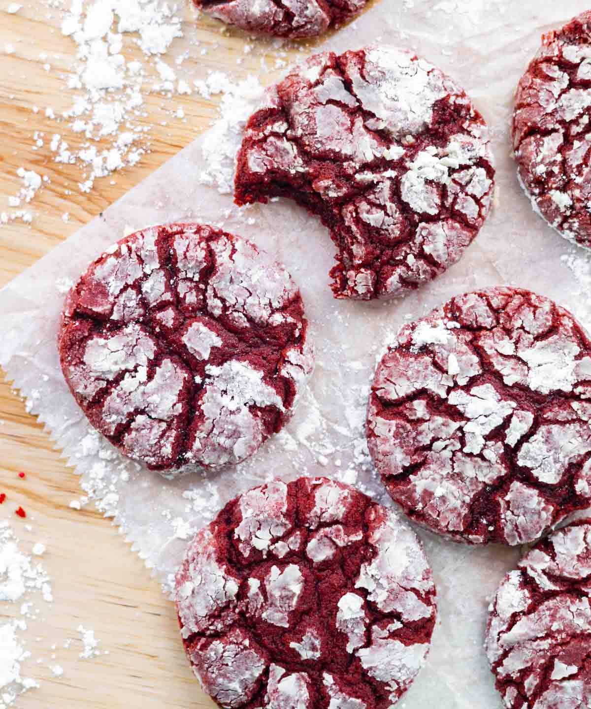 Red velvet crinkle cookies on a wooden table.