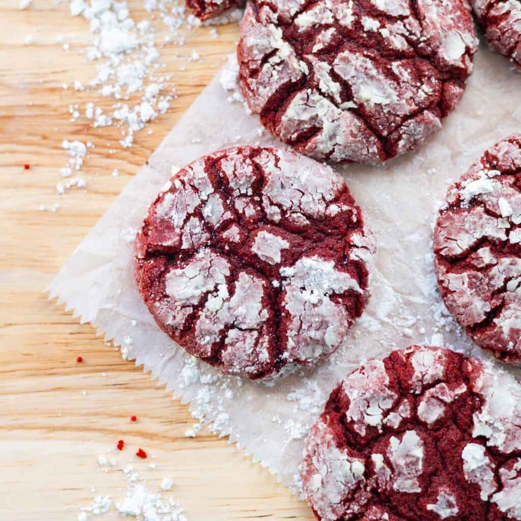 Red velvet crinkle cookies on a wooden table.