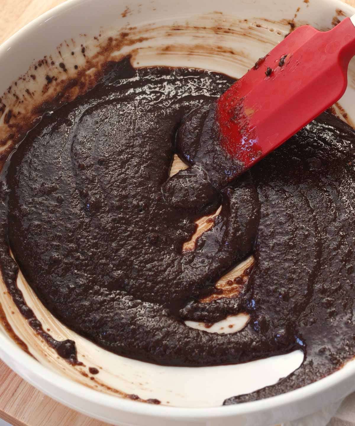 Mixed melted butter, sugars, and cocoa powder in white bowl.