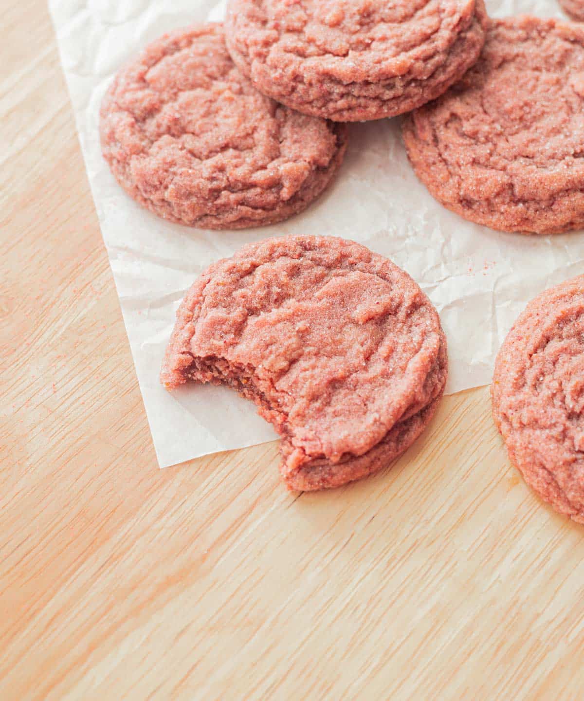 Strawberry sugar cookie with a bite taken out of it.