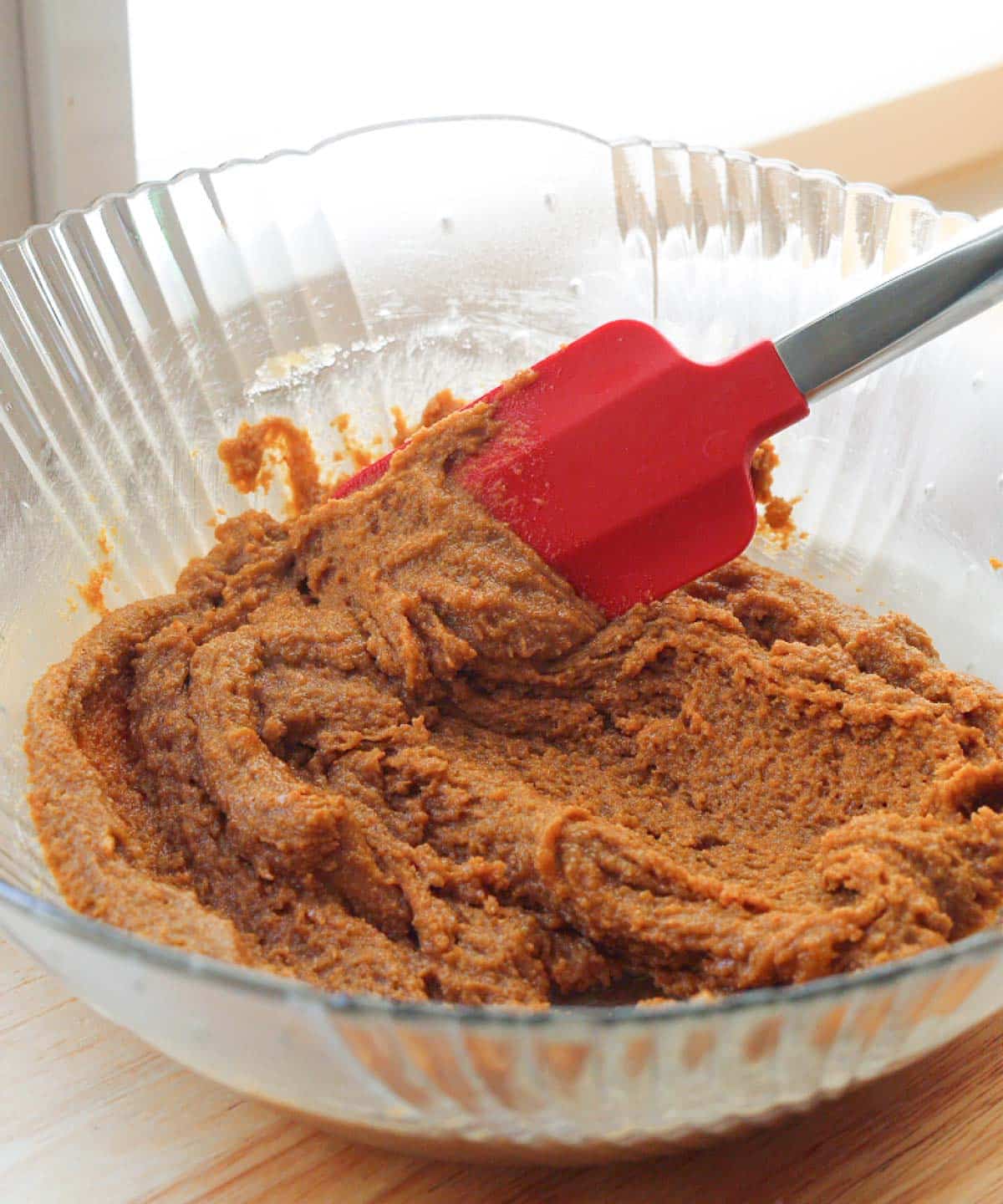 Melted butter mixed with peanut butter and sugars in glass mixing bowl.