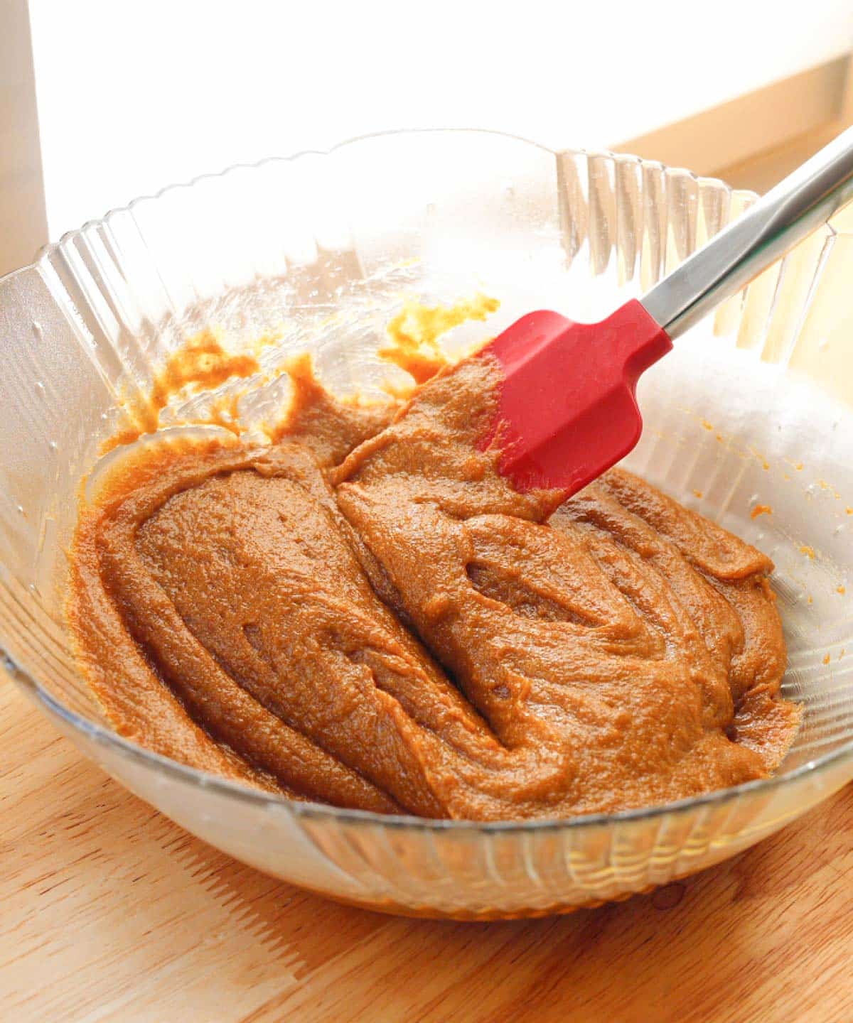 Mixed wet ingredients in glass mixing bowl, forming a silky smooth batter.