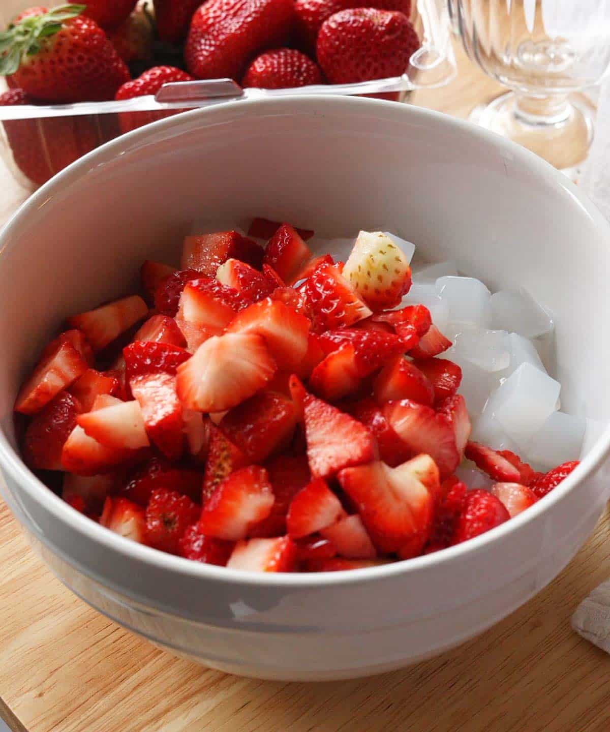 Tapioca pearls, nata de coco, and diced strawberries in a large white serving bowl.