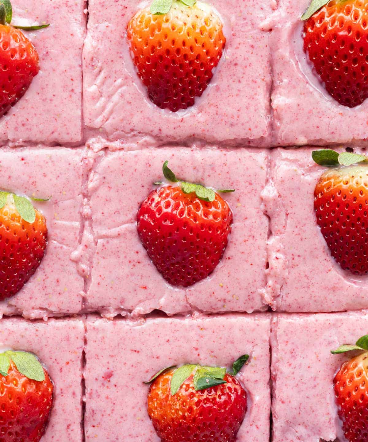 Frosted strawberry brownies topped with fresh strawberries.