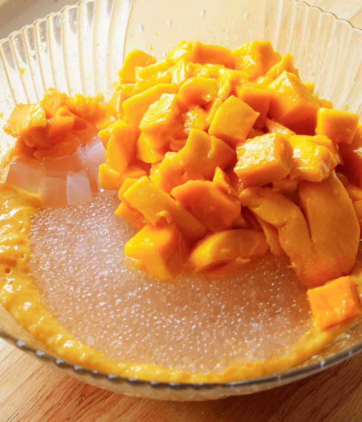 Tapioca pearls, nata de coco, and diced mangoes in a large glass serving bowl.