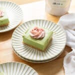 No bake matcha cheesecake bar topped with strawberry whipped cream on a fluted plate.