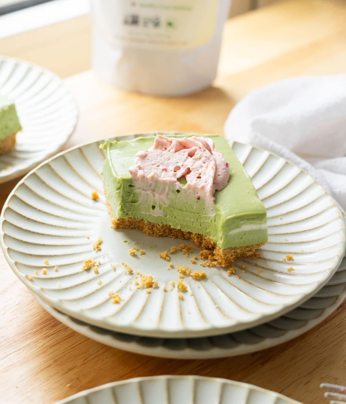 Matcha cheesecake bar with a bite taken out of it, showing the creamy texture.
