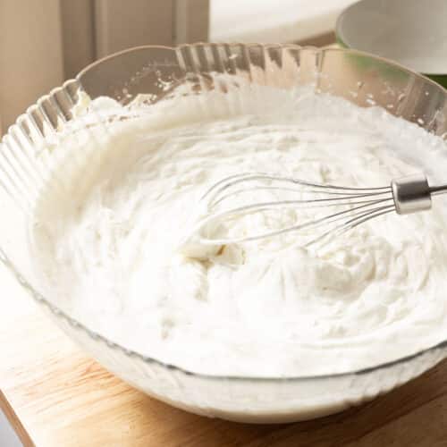 Stabilized whipped cream frosting in a glass mixing bowl.