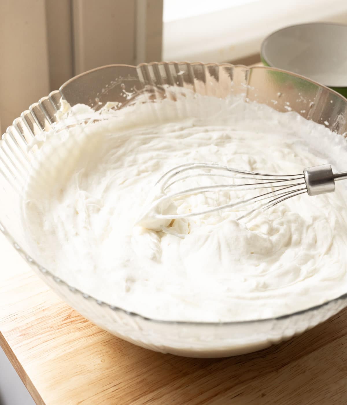 Stabilized whipped cream frosting in a glass mixing bowl.