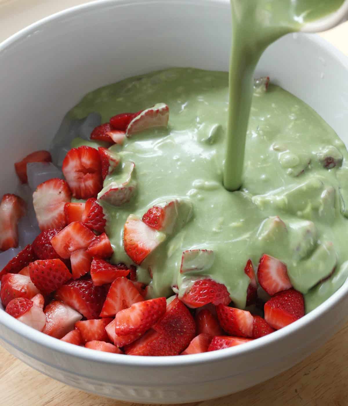 Pouring matcha mixture over sago ingredients.