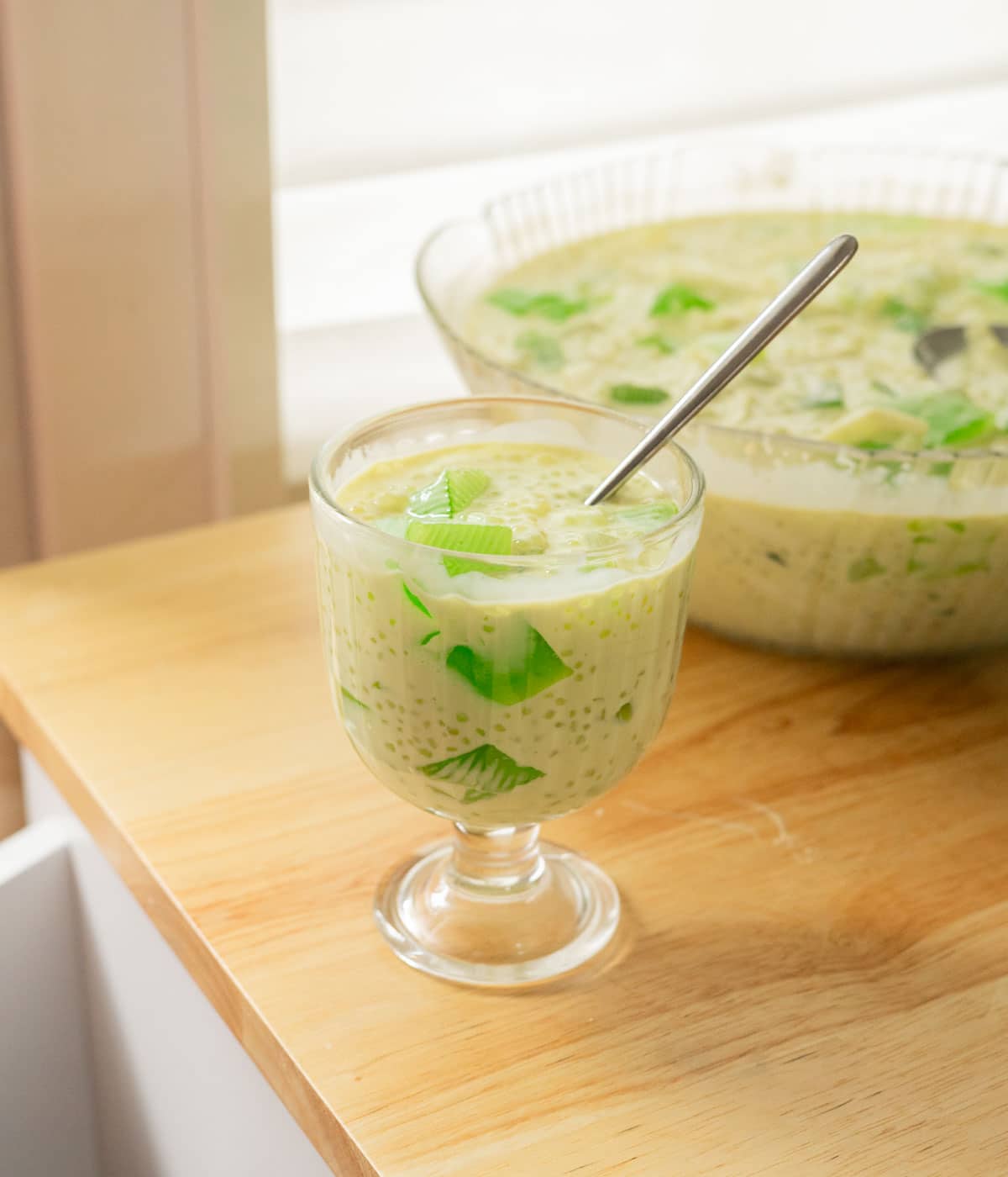 Buko pandan in a glass serving cup on a wooden table.