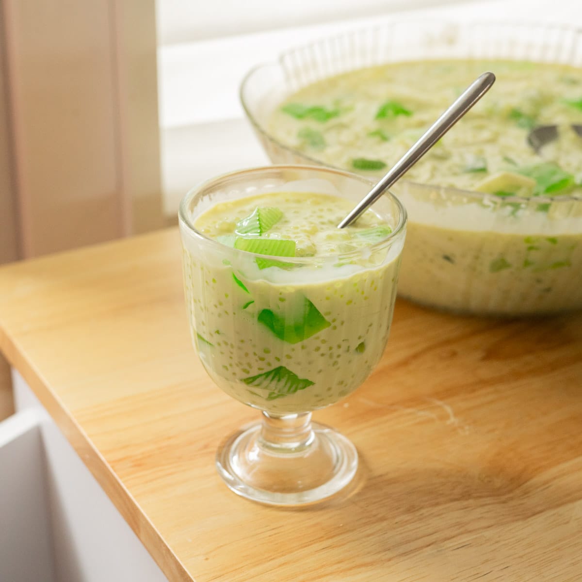 Buko pandan in a glass serving cup on a wooden table.