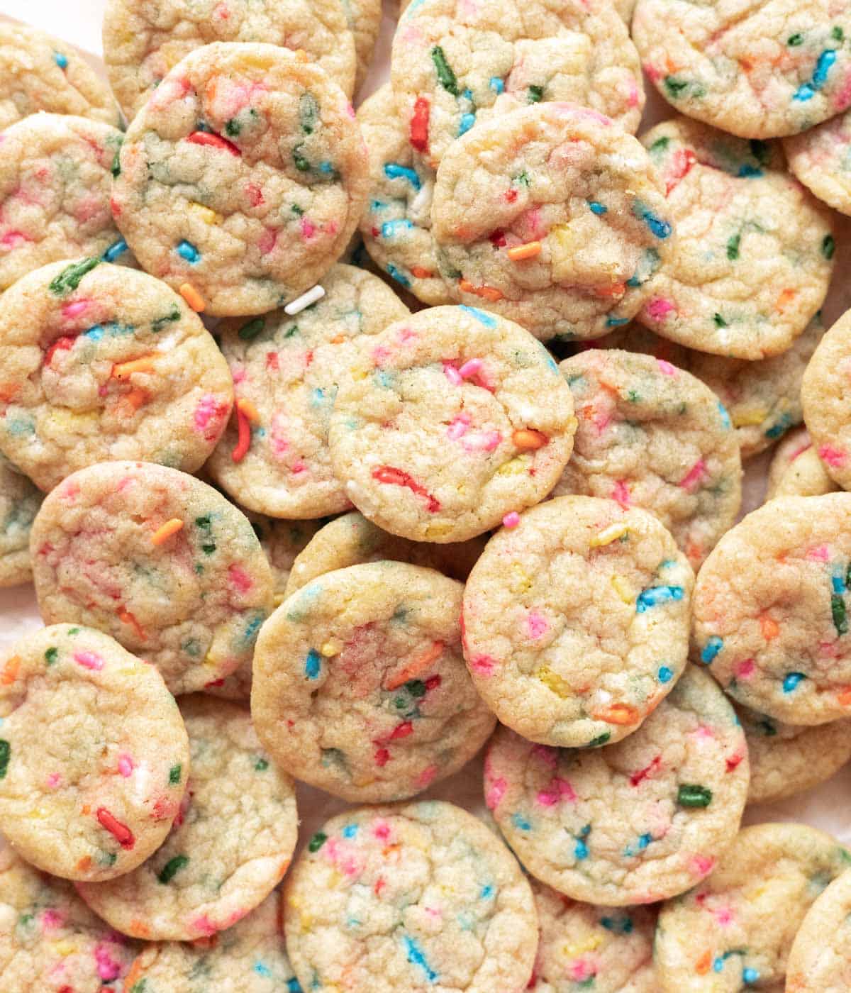 Mini funfetti cookies spread out on parchment paper.