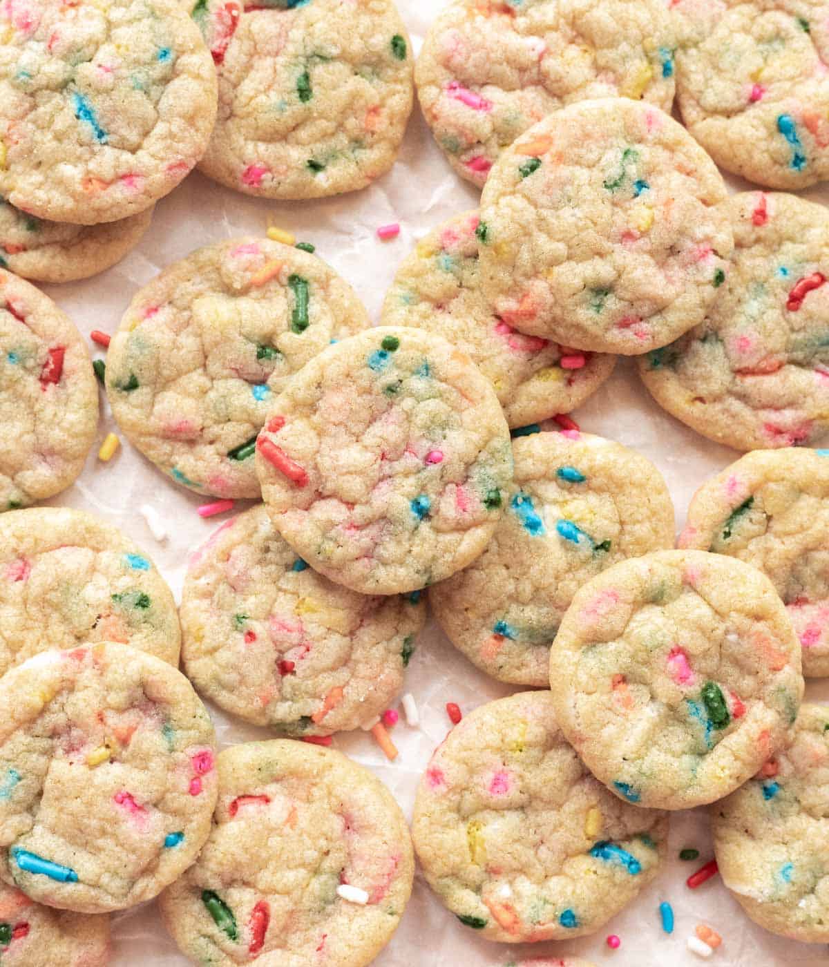 Mini funfetti cookies spread out on parchment paper.