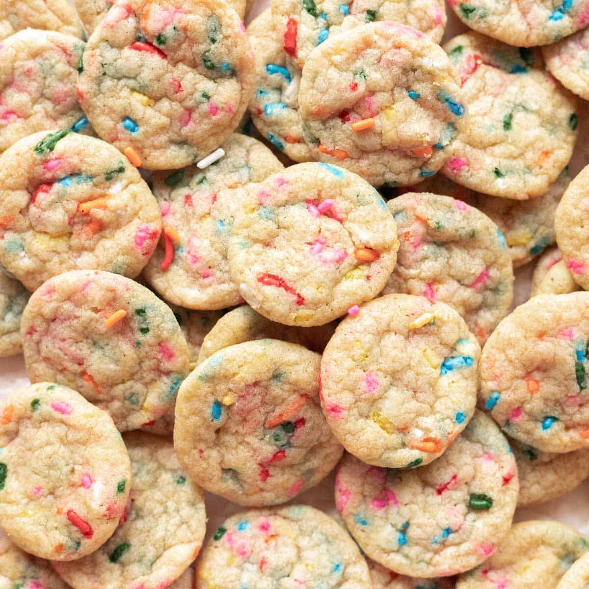 Mini funfetti cookies spread out on parchment paper.
