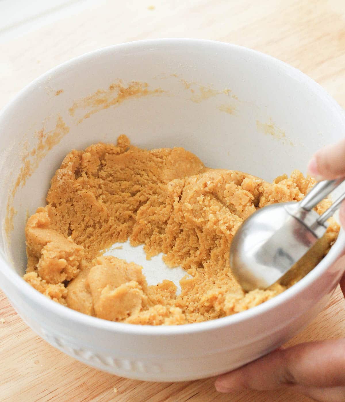 Using a medium cookie scoop to gather corn cookie dough.