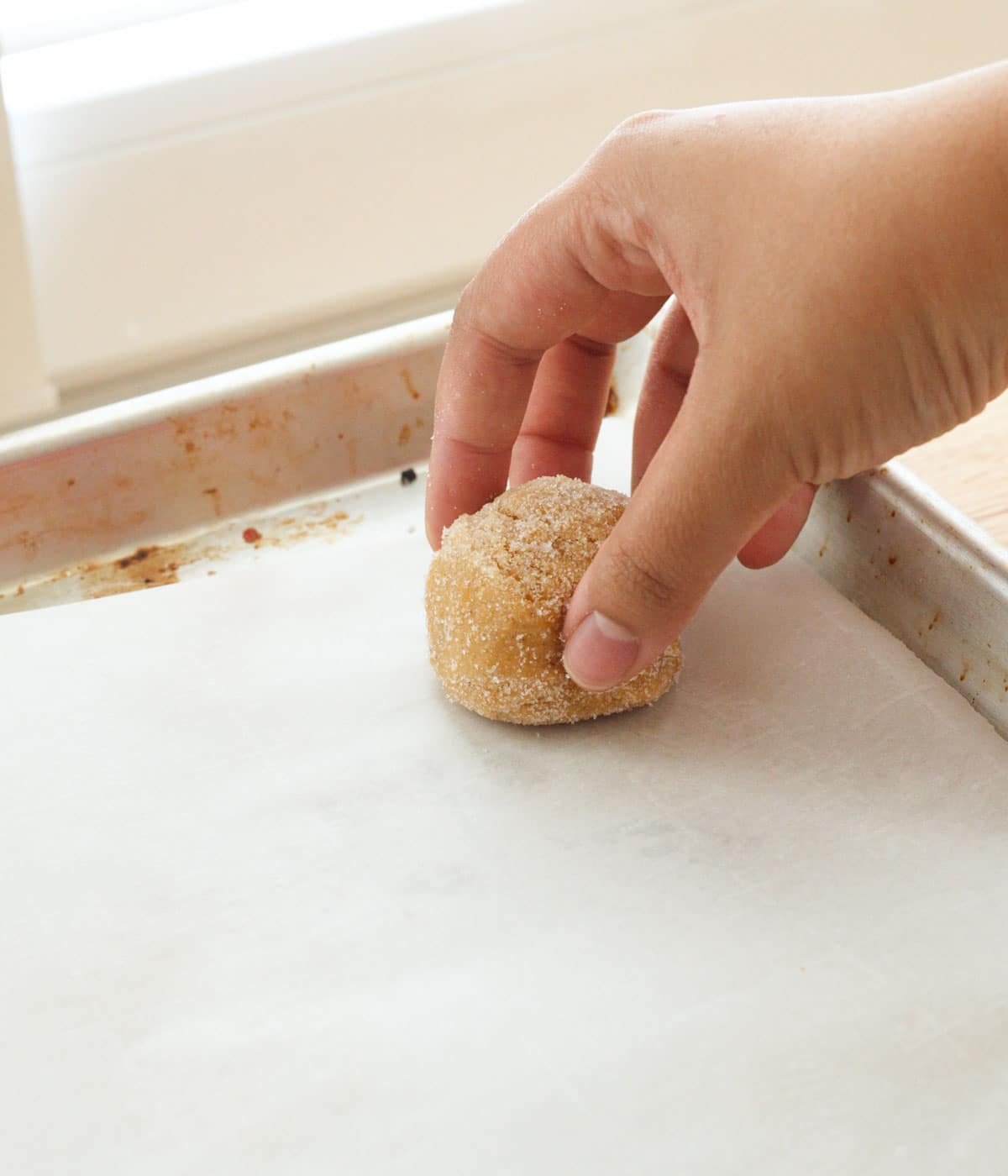 Placing cookie dough ball on lined baking sheet.
