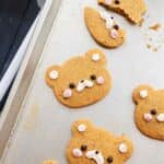 Rolled out corn cookies on a cookie sheet, all decorated as bears.