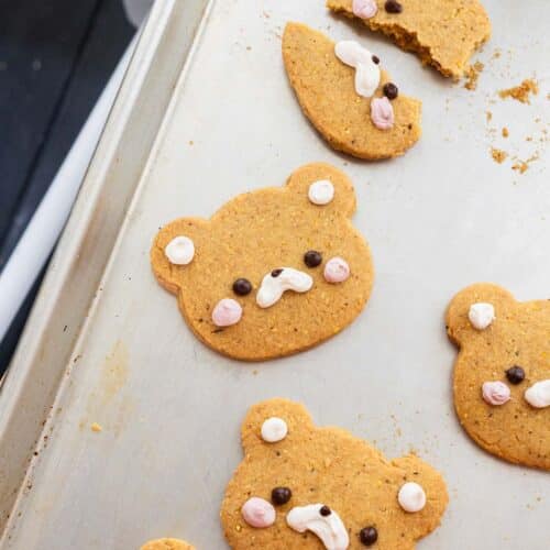 Rolled out corn cookies on a cookie sheet, all decorated as bears.