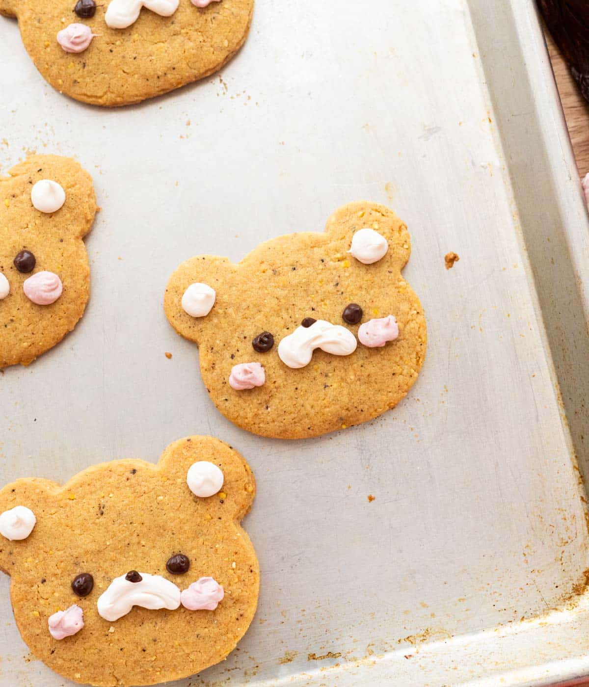 Rolled out corn cookies on a cookie sheet, all decorated as bears.