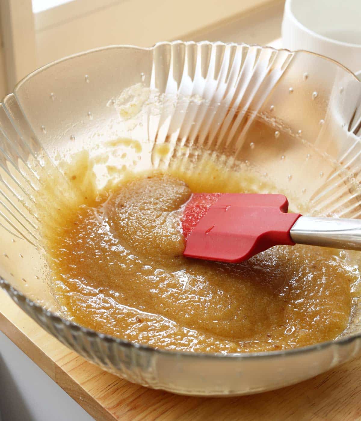 Sugar and butter mixed together in a glass mixing bowl.
