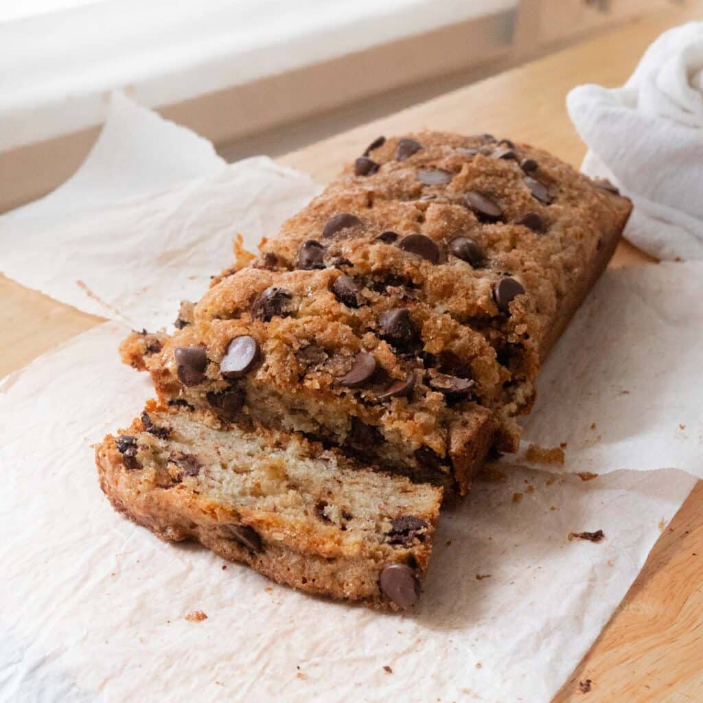Sliced chocolate chip banana bread on white parchment paper.